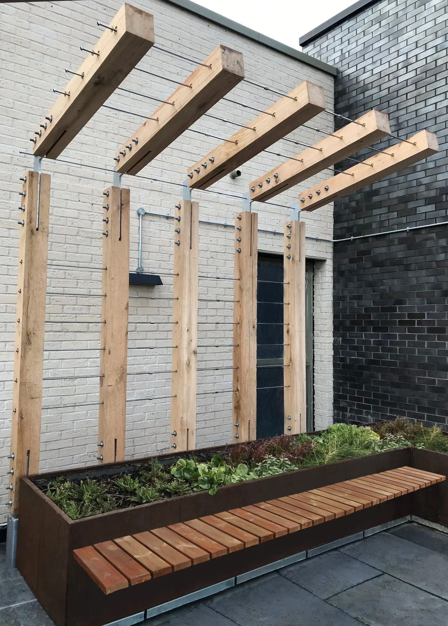 Outdoor wooden L shaped pergola with metal wired between pillars