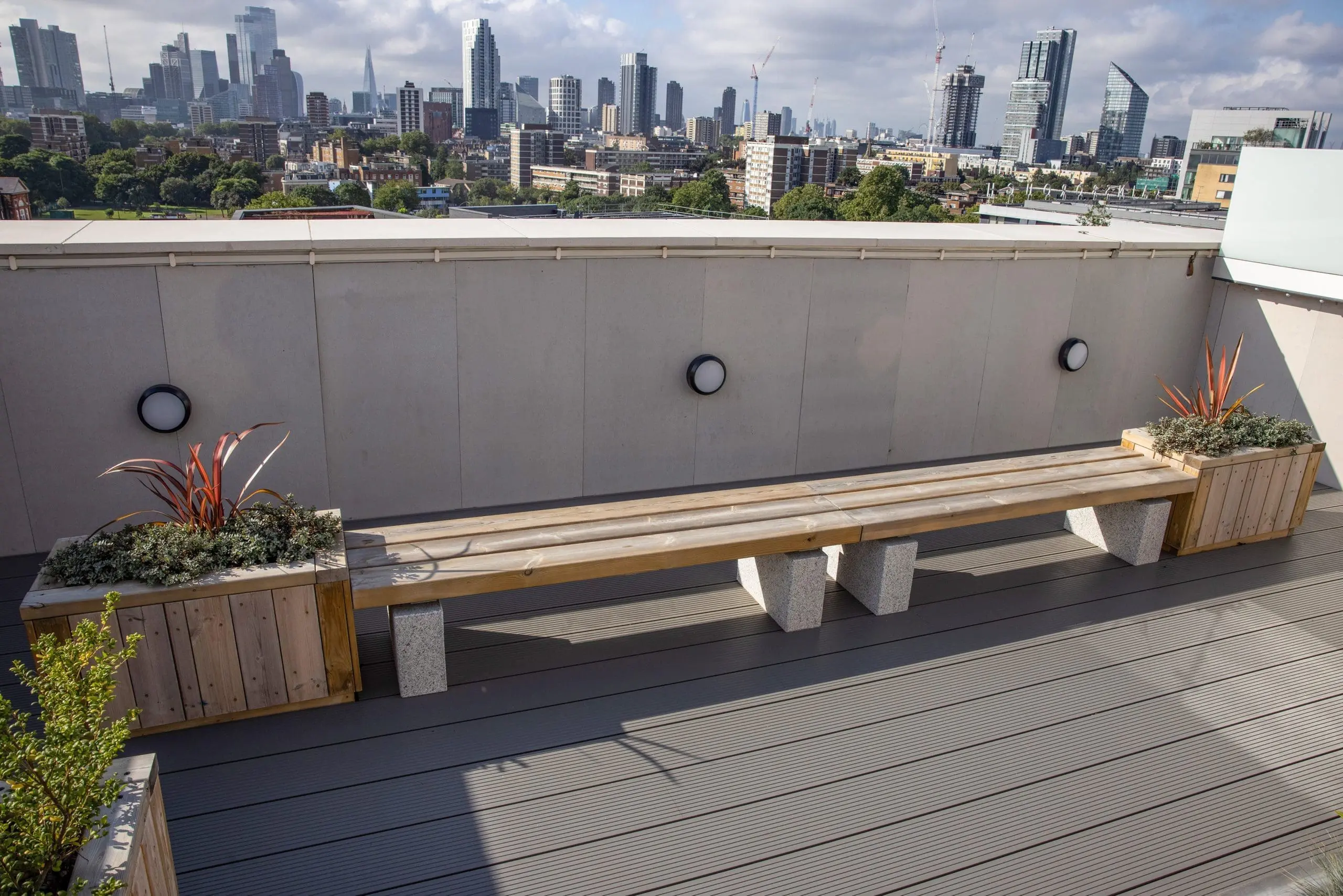 outdoor rooftop wooden planters left and right of wooden bench with concrete plinth legs