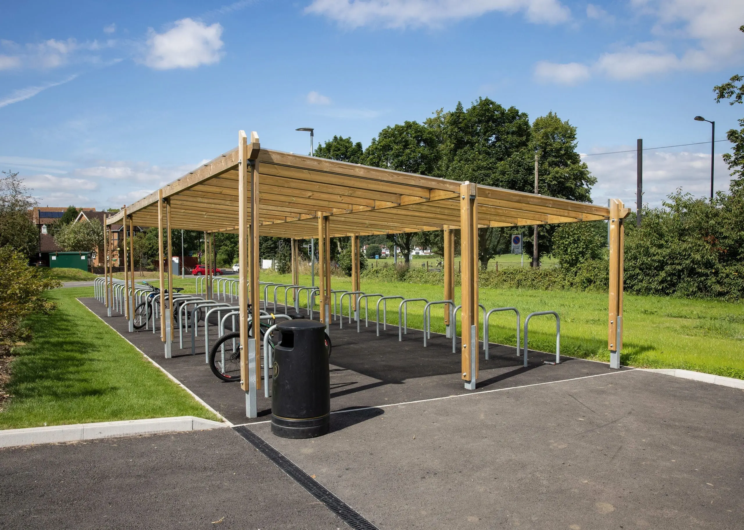 two rows of metal bike lock hoops with half under wooden pergola shelter