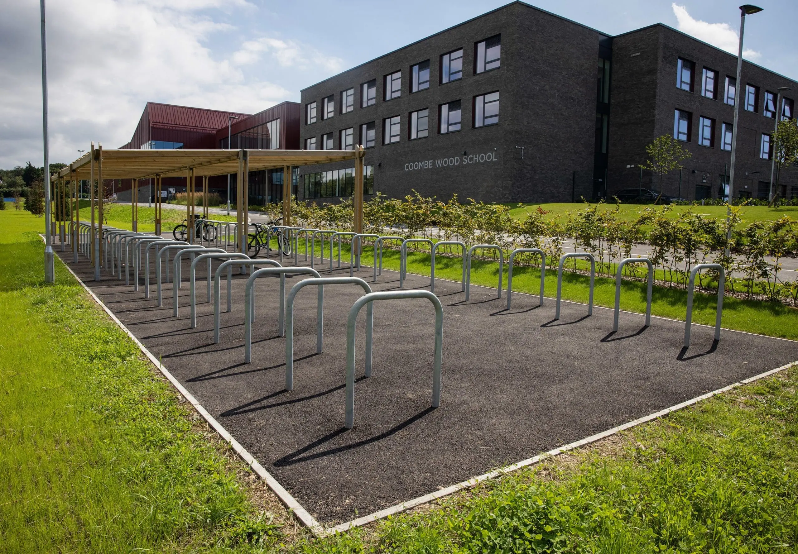 two rows of metal bike lock hoops with half under wooden pergola shelter