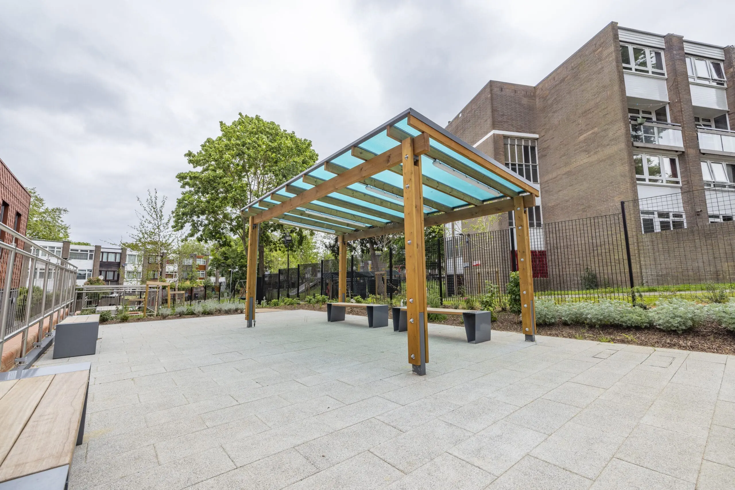 Wooden shelter with a covering, benches are placed underneath.