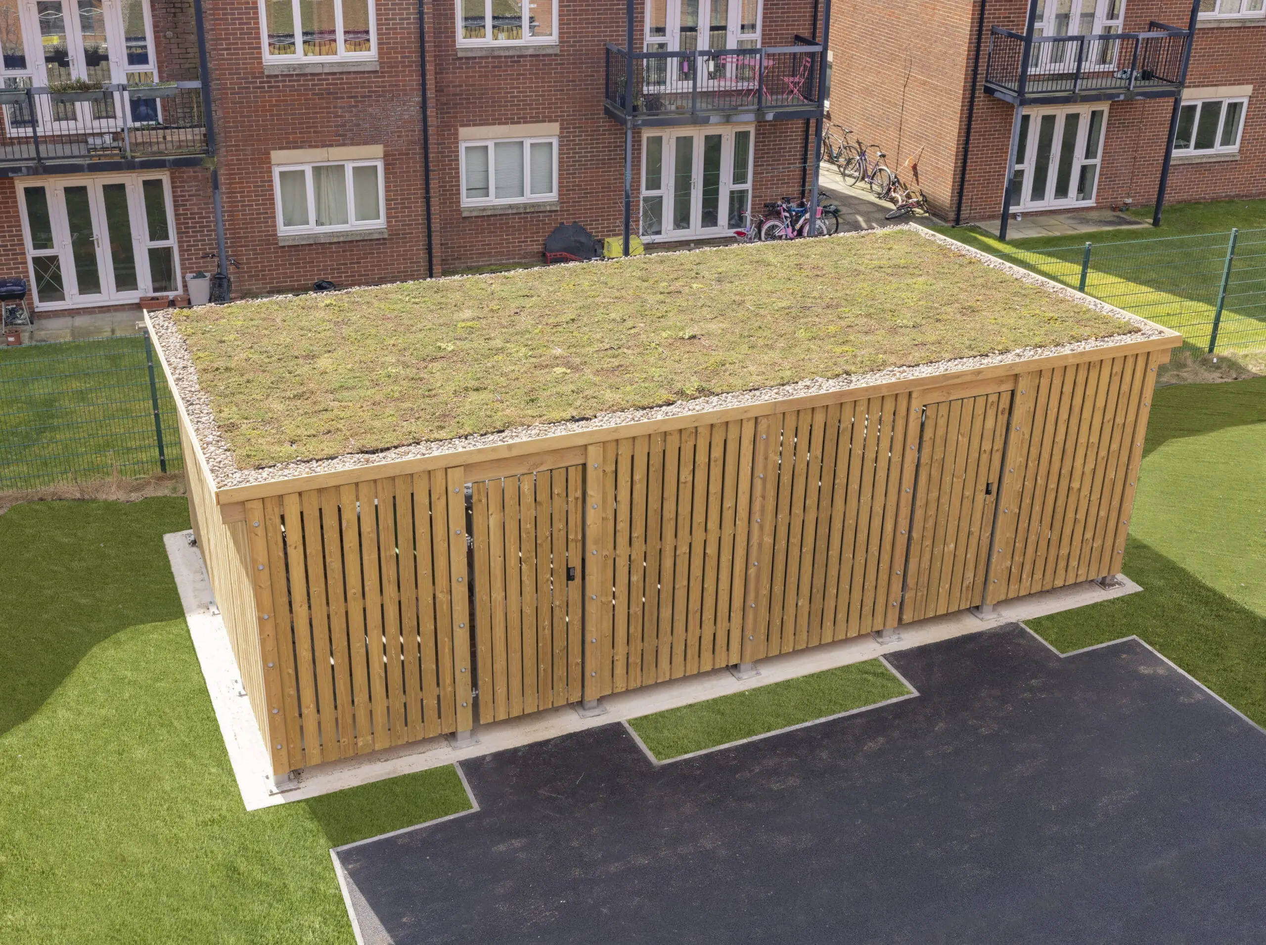 Wooden storage building with two doors, and grass/shrubs growing on the roof.