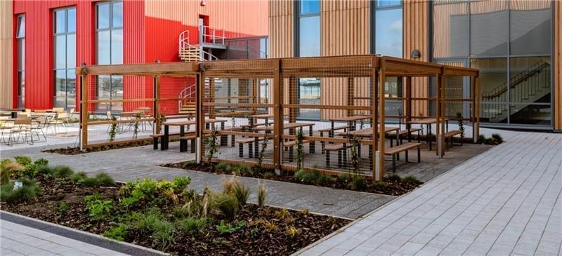 benches under canopy infront of red building