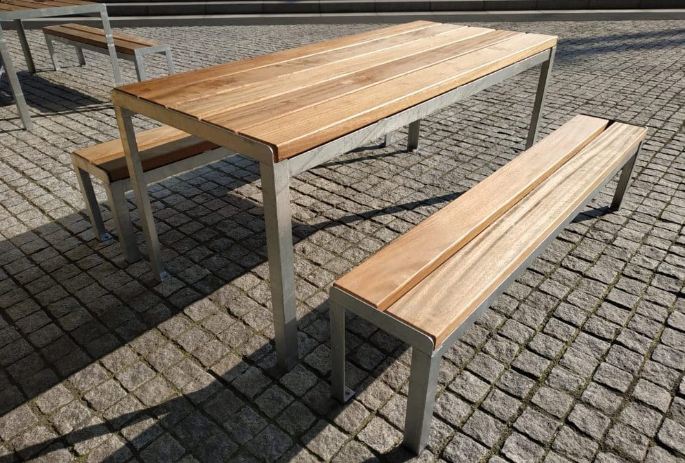 Closeup of wooden picnic table and matching benches with silver metal legs