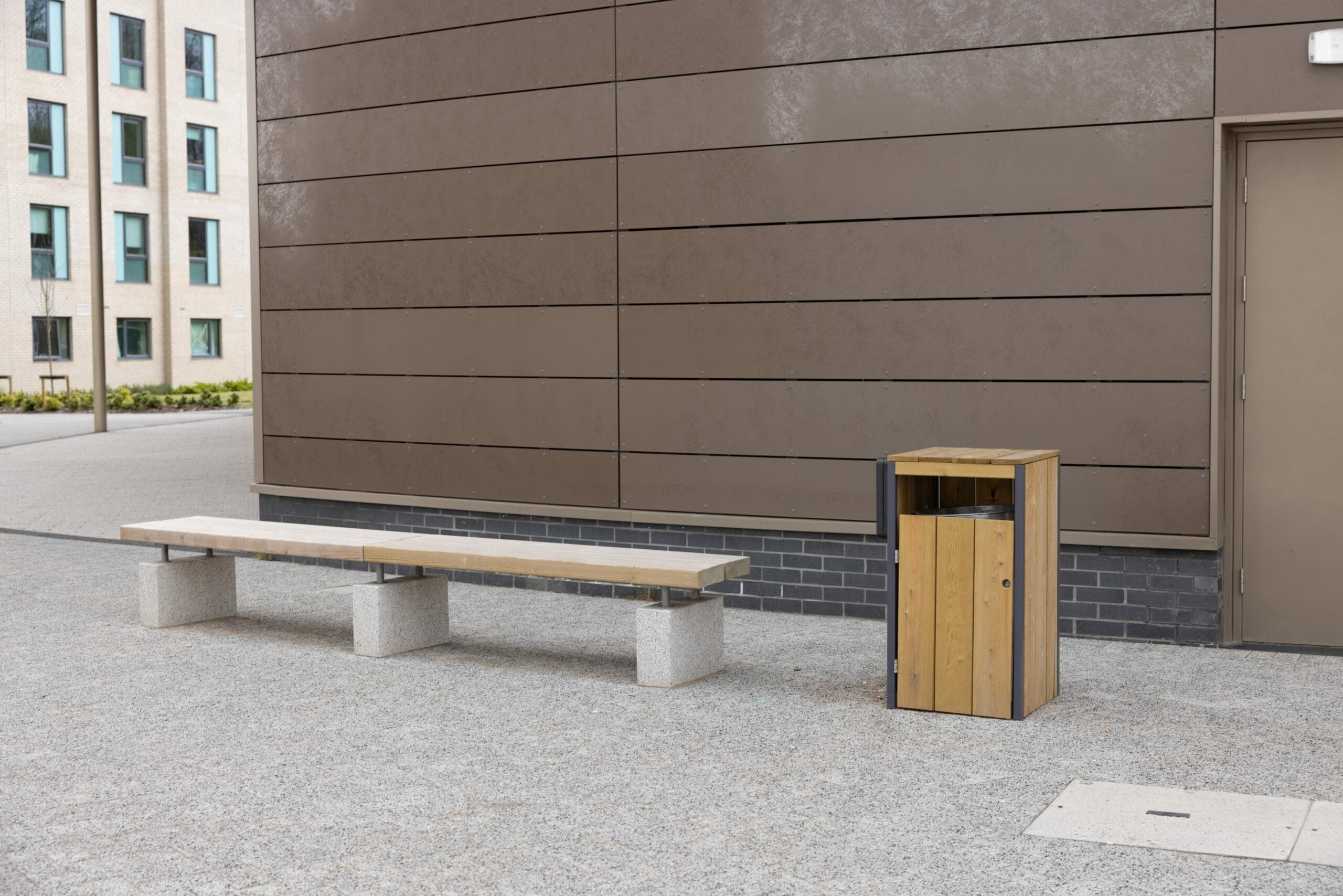 outdoor wooden bench with concrete plinth legs next to wooden and metal bin