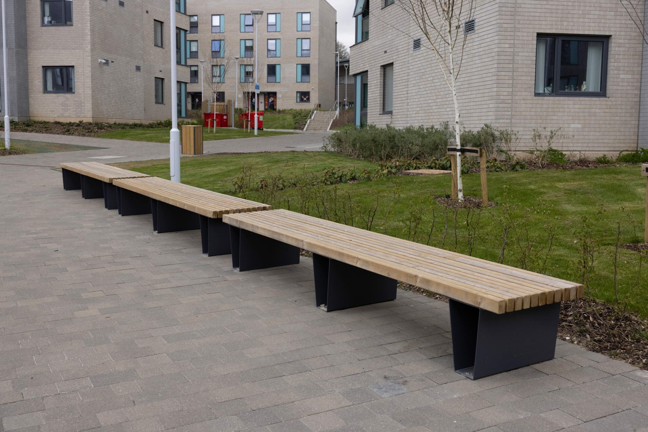 Row of outdoor wooden benches with black metal V shaped legs