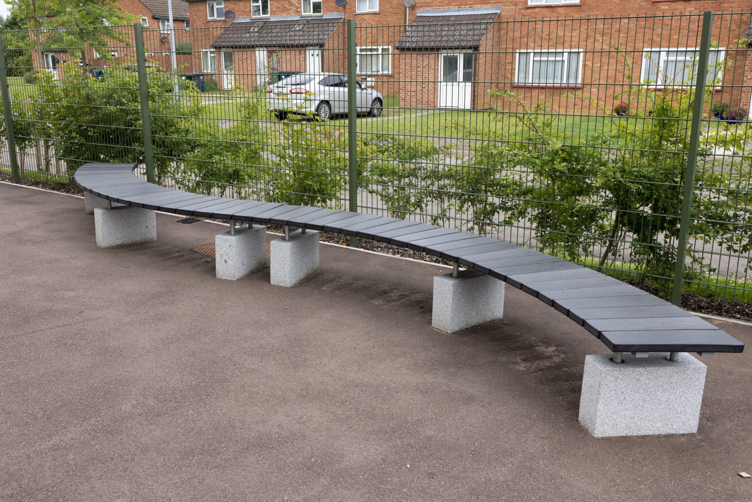 S shaped curved outdoor bench black wood concrete plinths