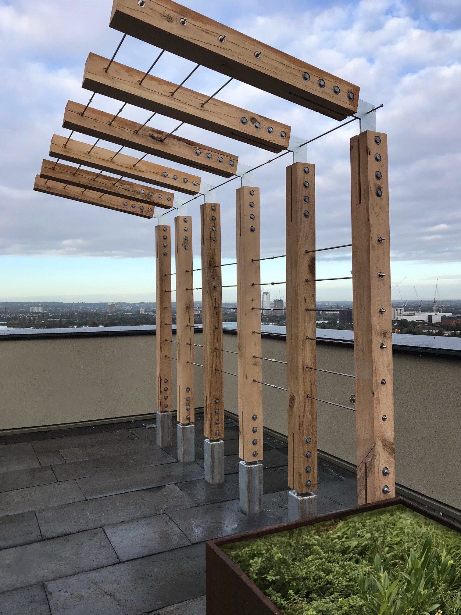 Outdoor wooden L shaped pergola with metal wired between pillars