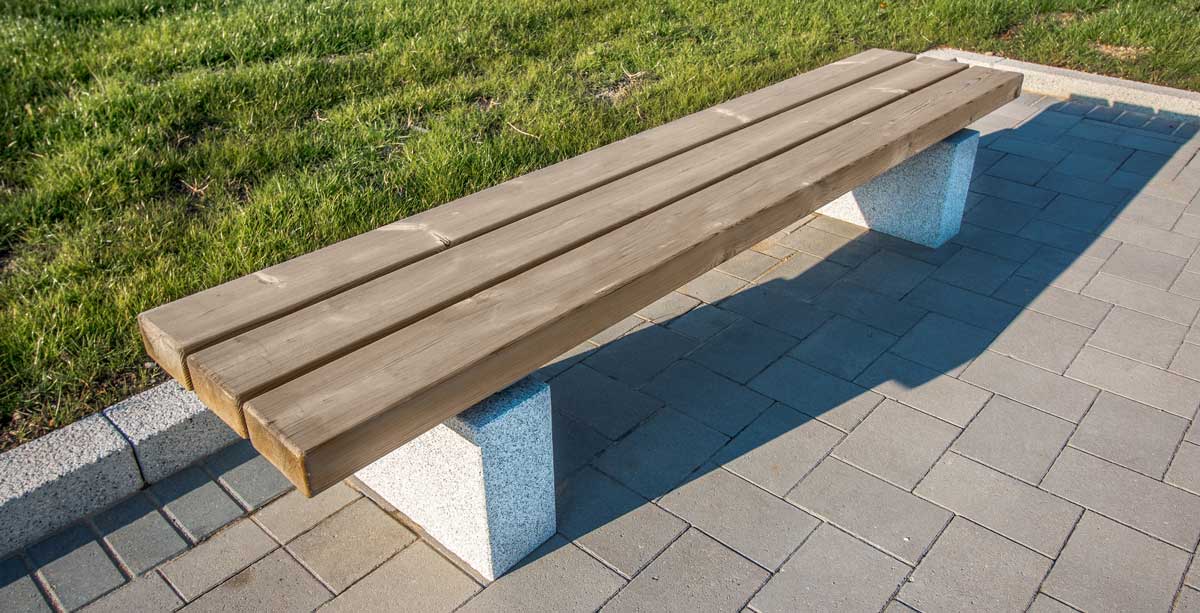 Wooden bench with concrete plinth legs by grassy area