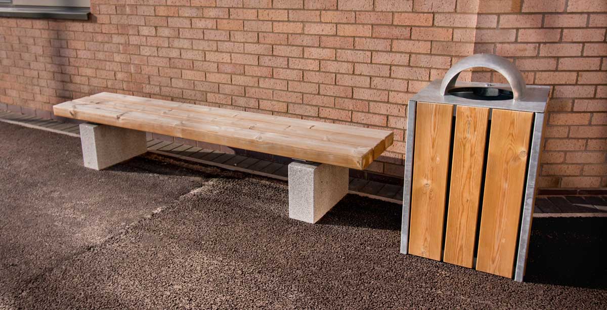 Wooden bench with concrete plinth legs next to wooden and metal bin