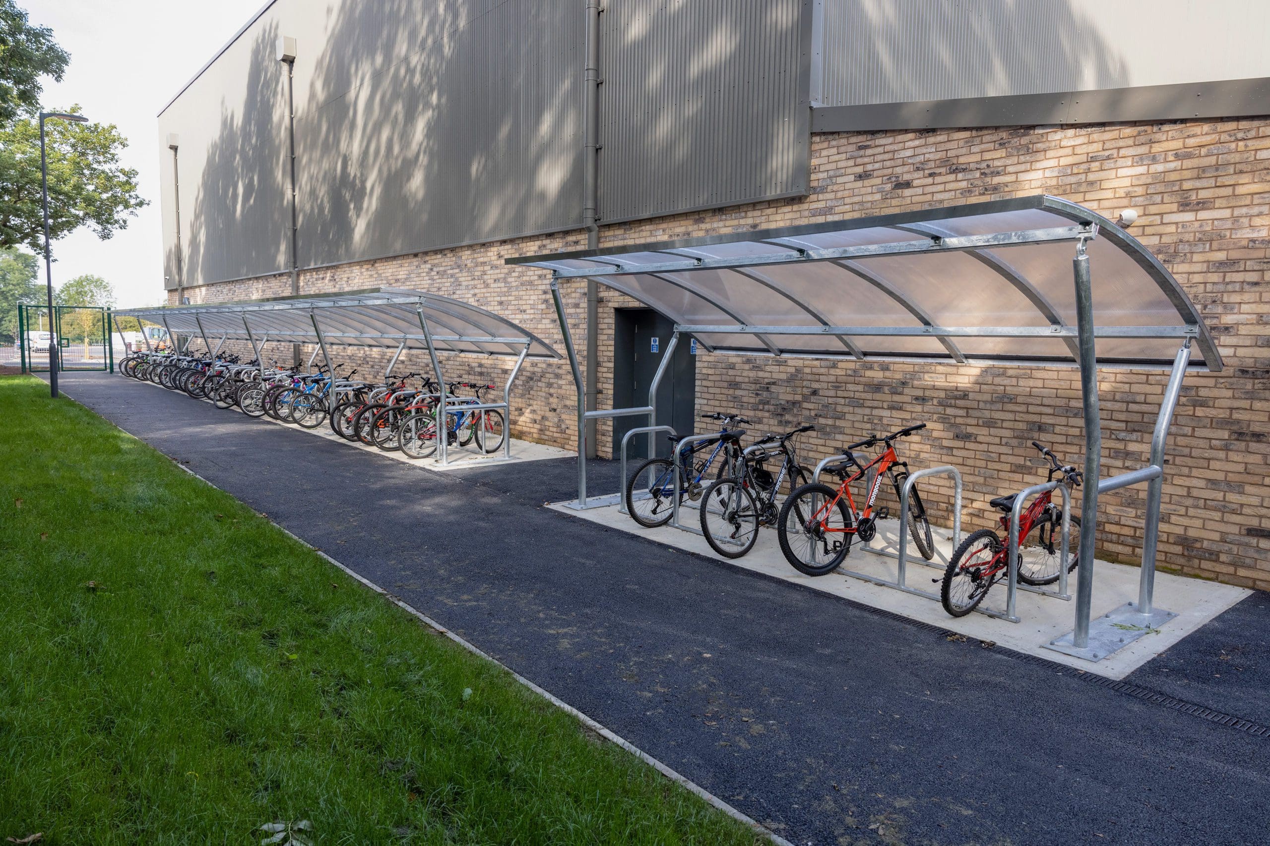 Row of metal outdoor bike racks with attached metal and see through canopy shelter