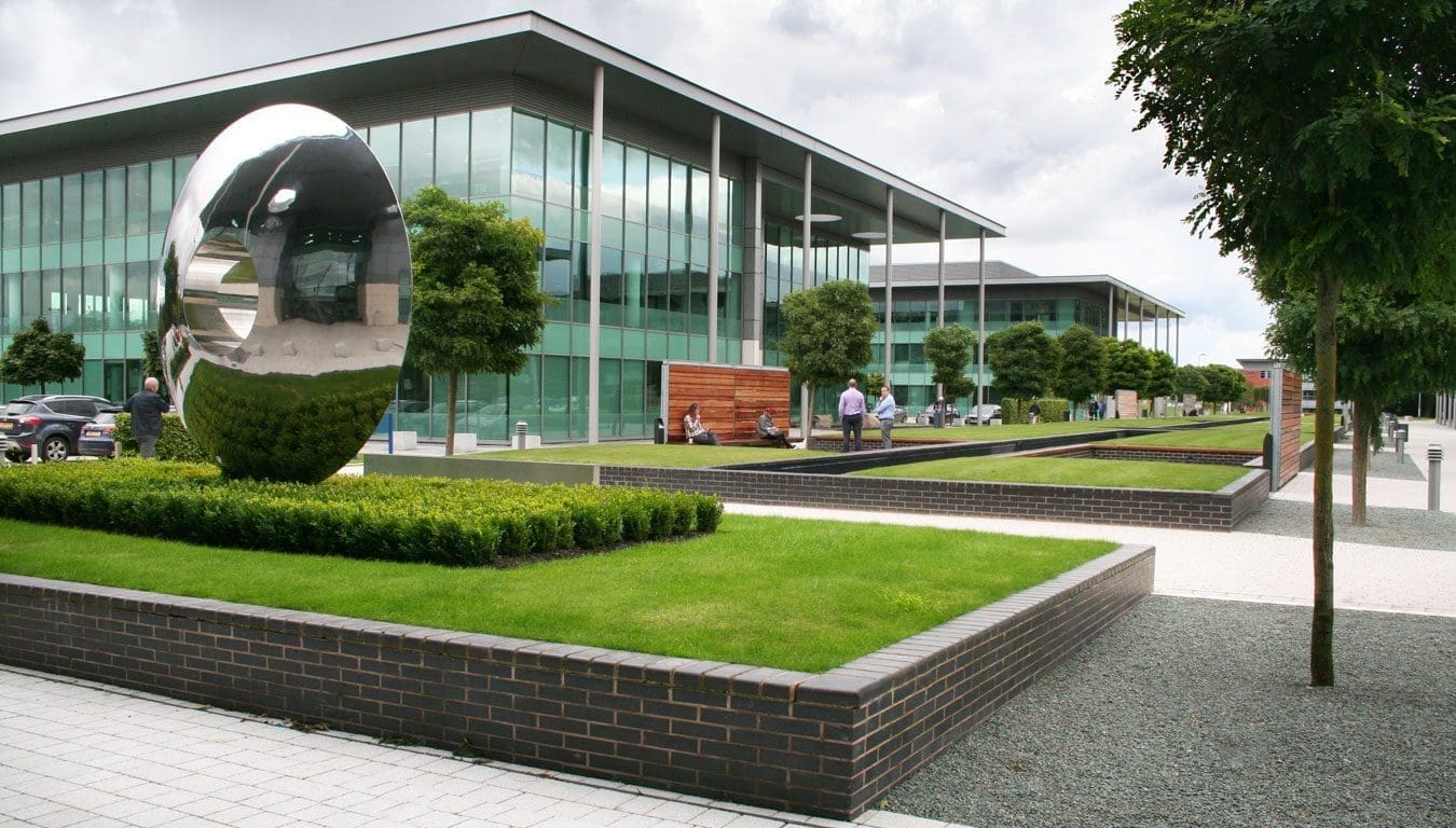 Wide shot of glass office building with raised walls for grass areas