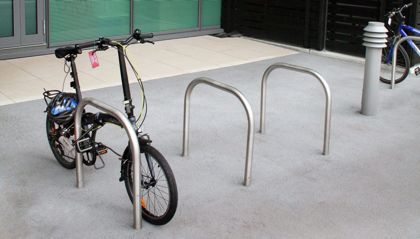 Metal hoop bicycle rack in concrete floor with bike attached