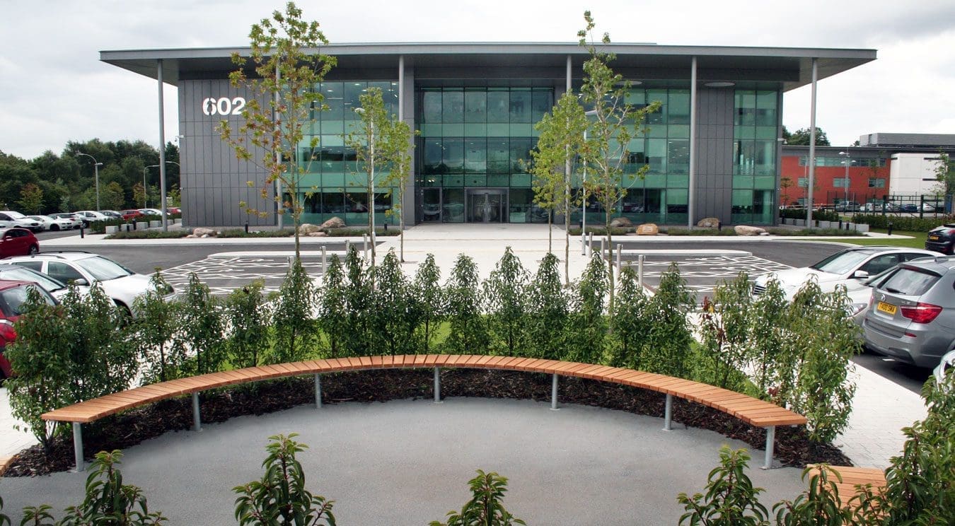Semicircle bench seating area surrounded by trees infront of office building
