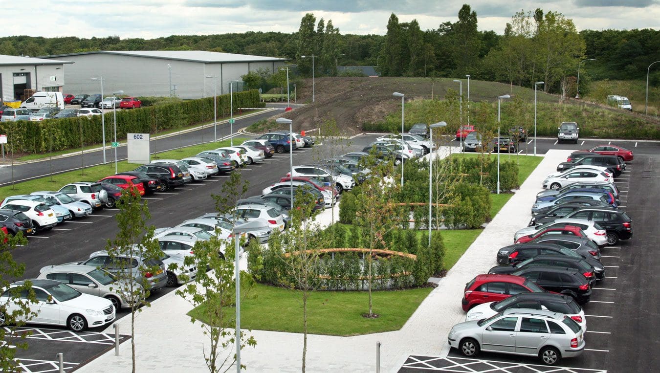 Birdseye view of business park carpark with 3 large circular bench seating areas surrounded by trees