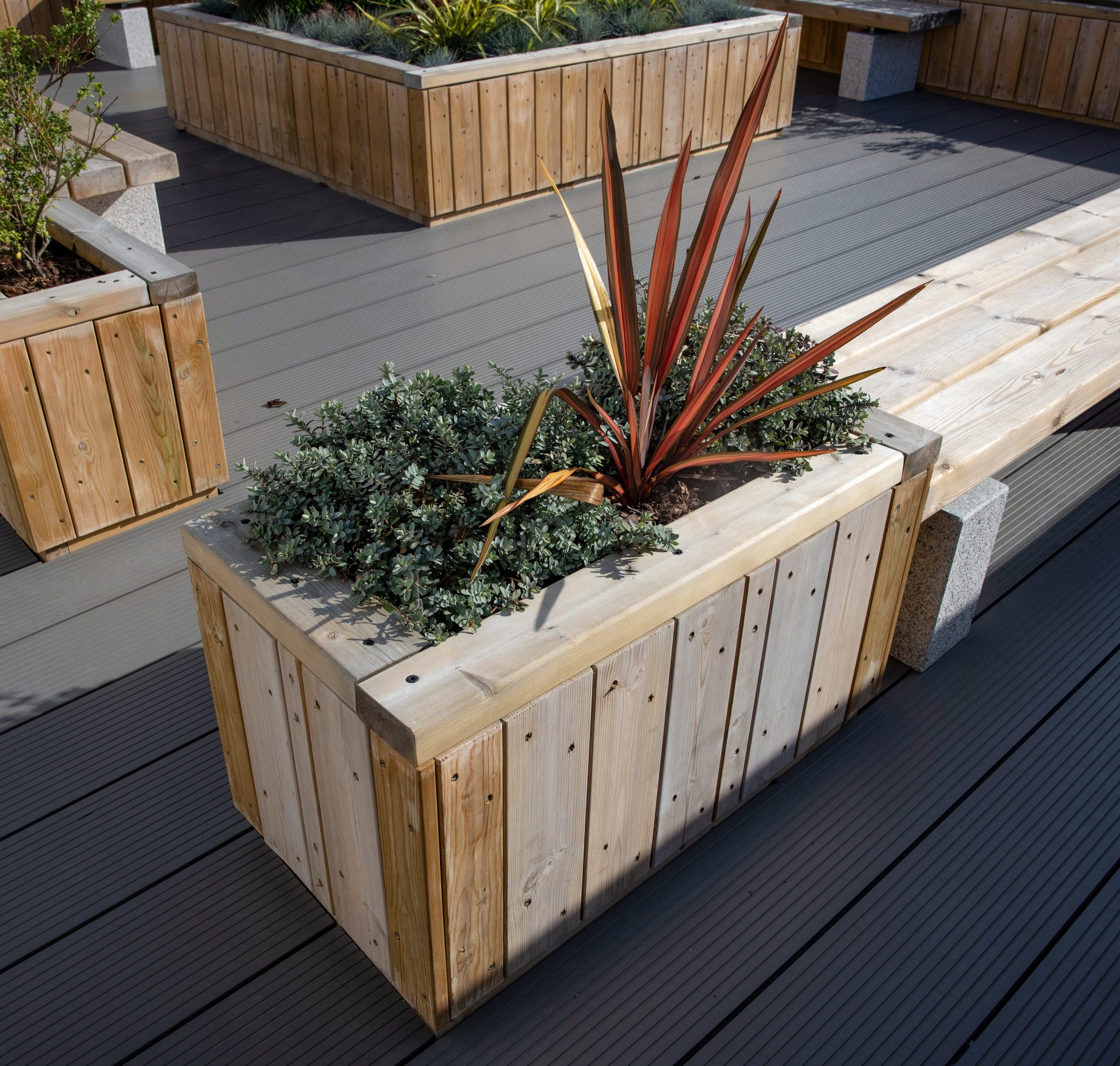 outdoor rooftop wooden planters next to wooden bench with concrete plinth legs
