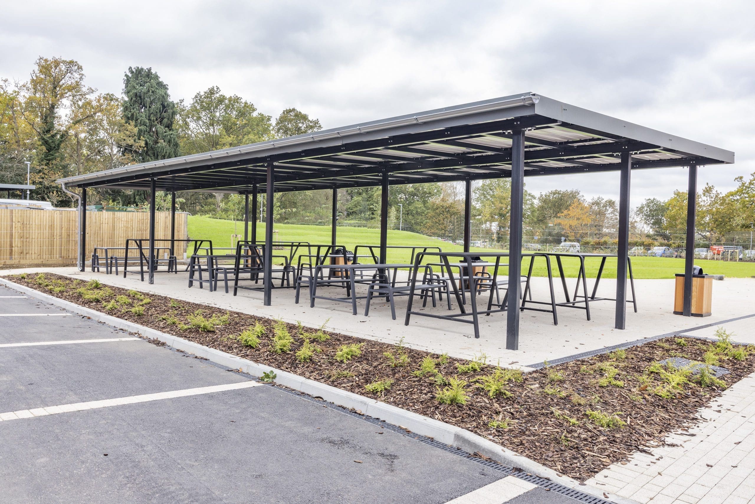 black-metal-outdoor-tables-and-benches-under-black-metal-pergola