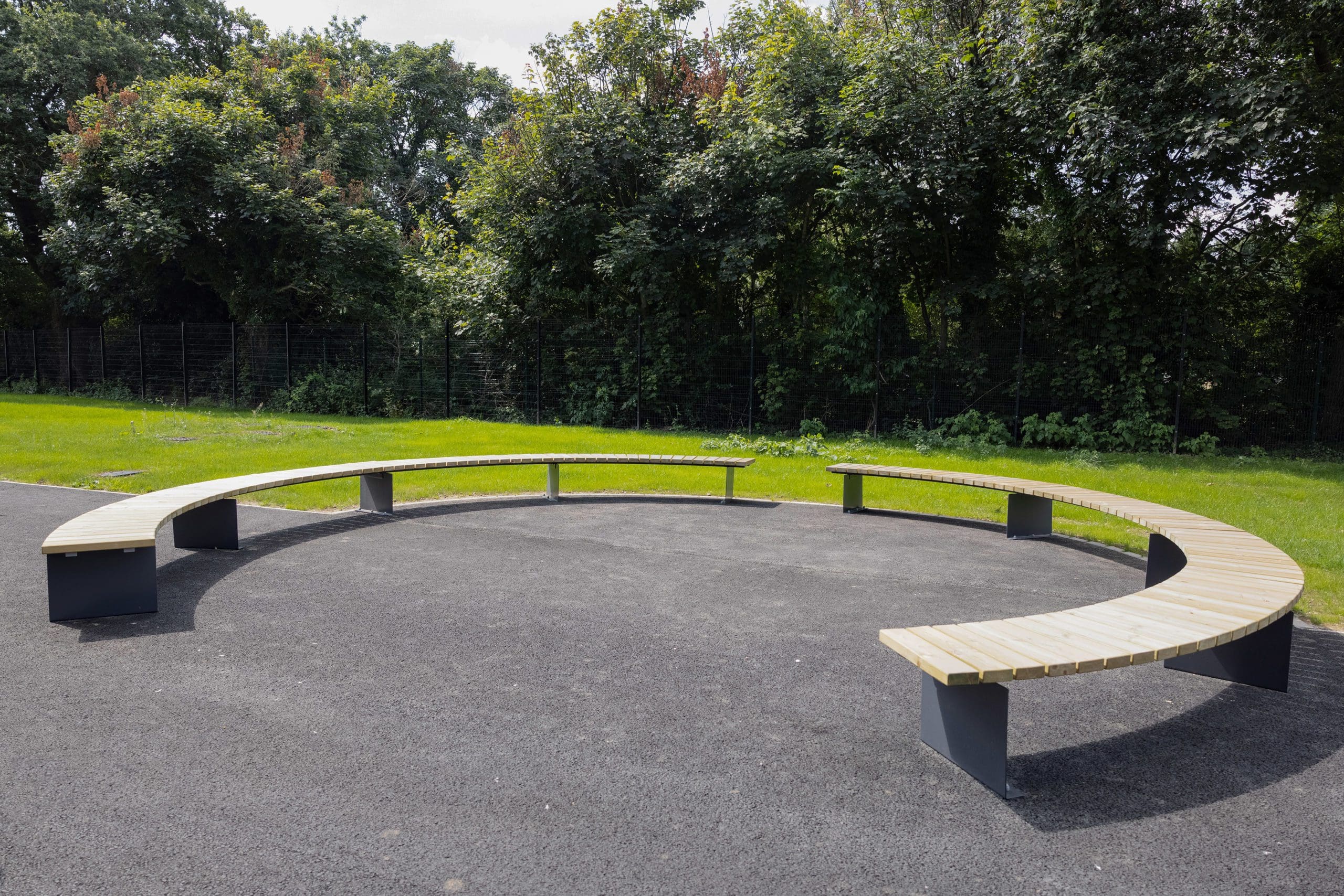 two semicircles of exterior curved benches wooden tops with dark grey metal legs