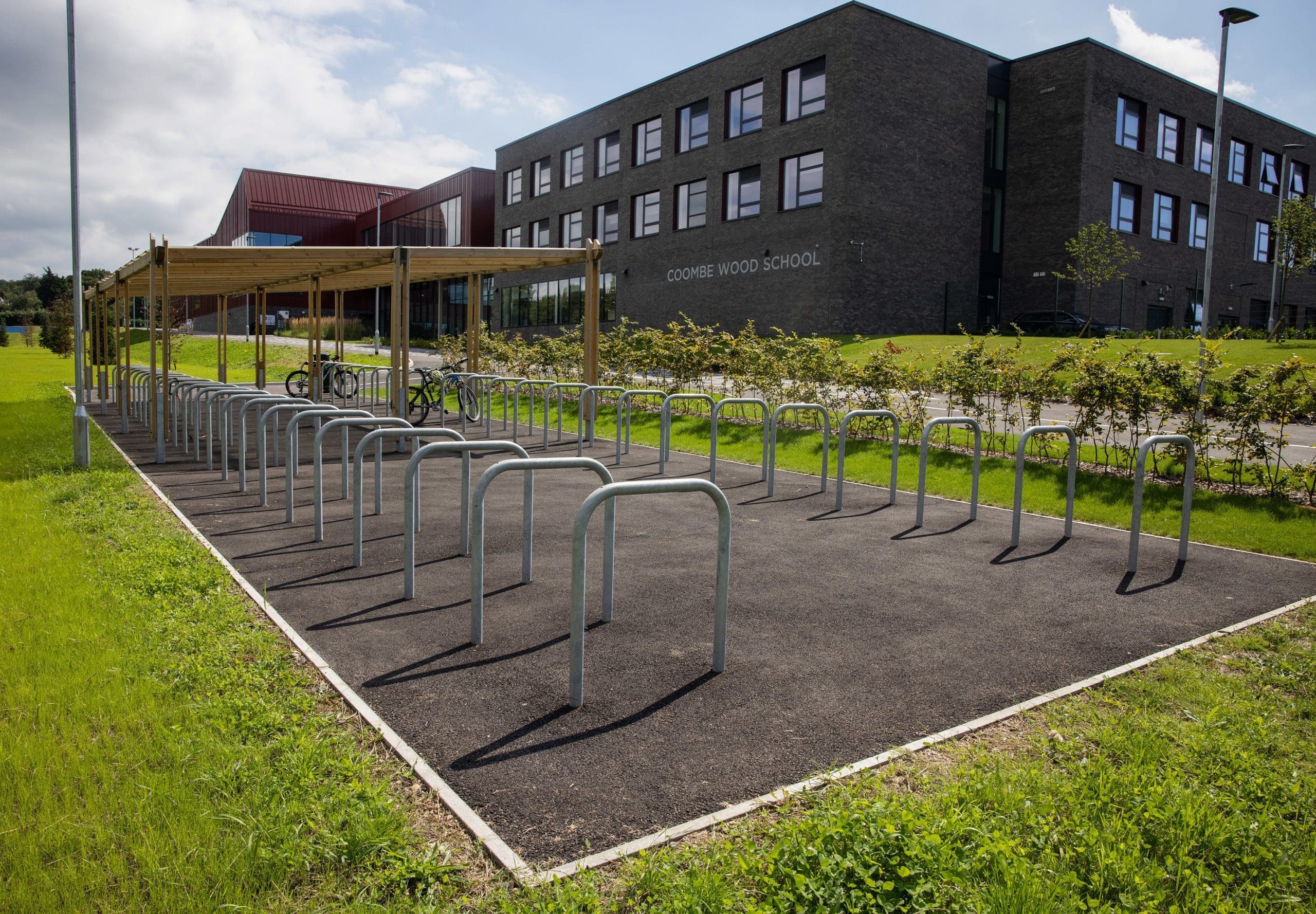 two rows of metal bike lock hoops with half under wooden pergola shelter