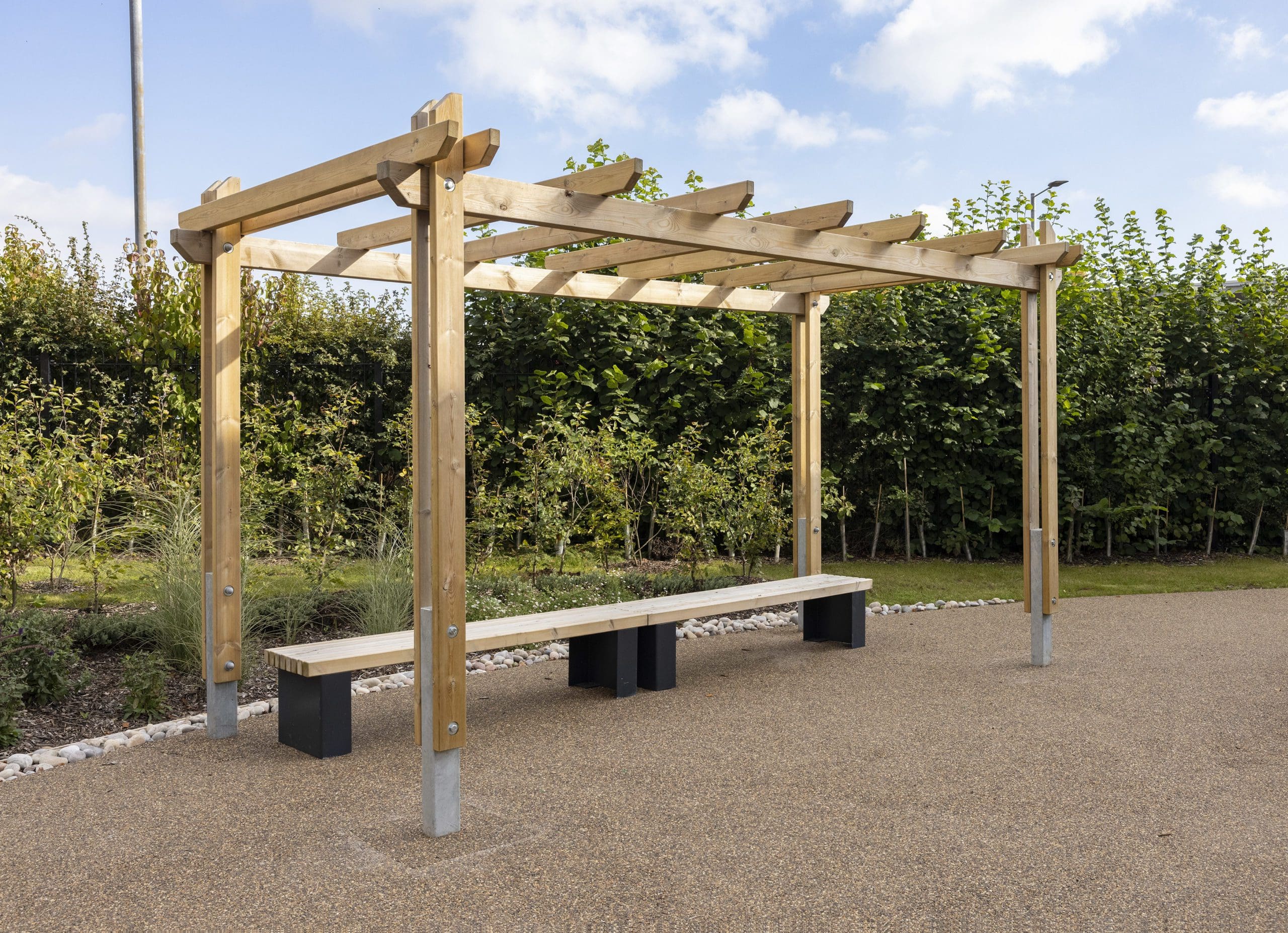 Outdoor wooden pergola canopy above two wooden benches with black plinth legs