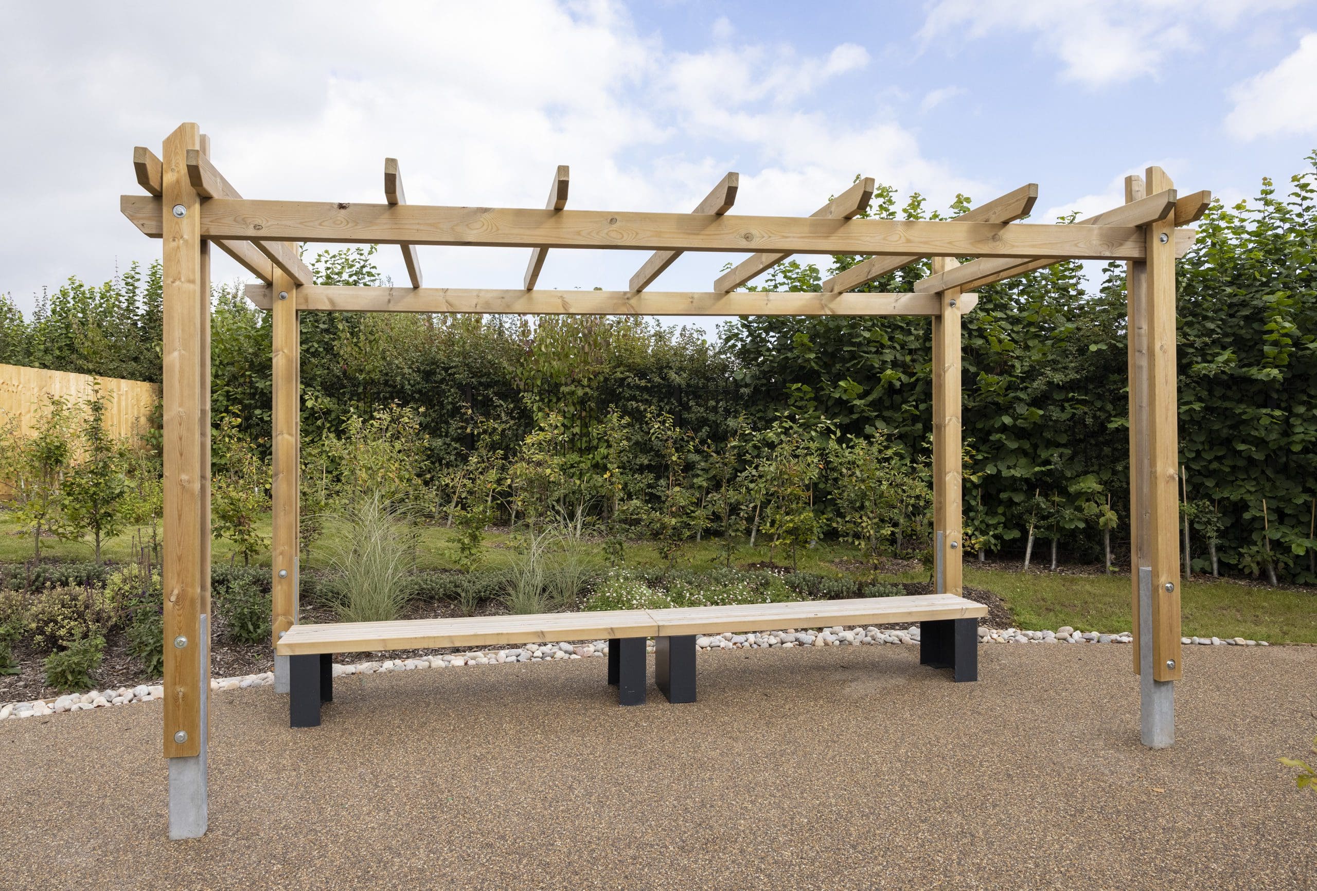 Outdoor wooden pergola canopy above two wooden benches with black plinth legs