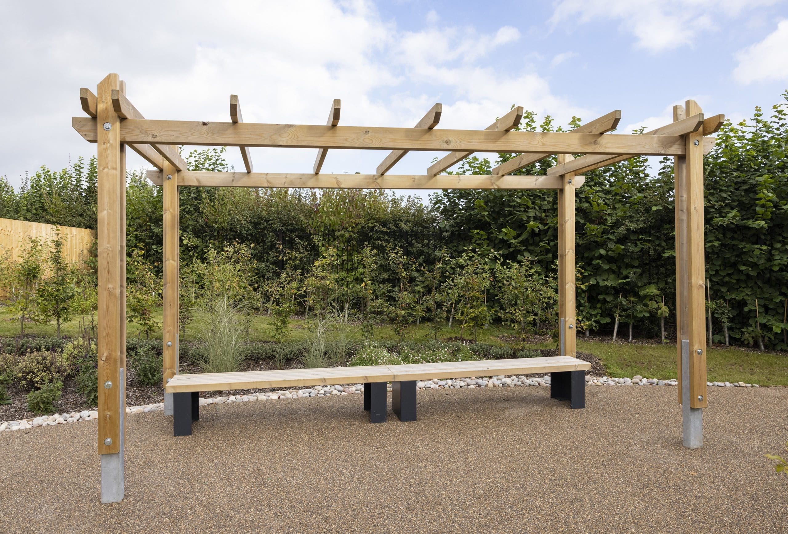 Outdoor wooden pergola canopy above two wooden benches with black plinth legs