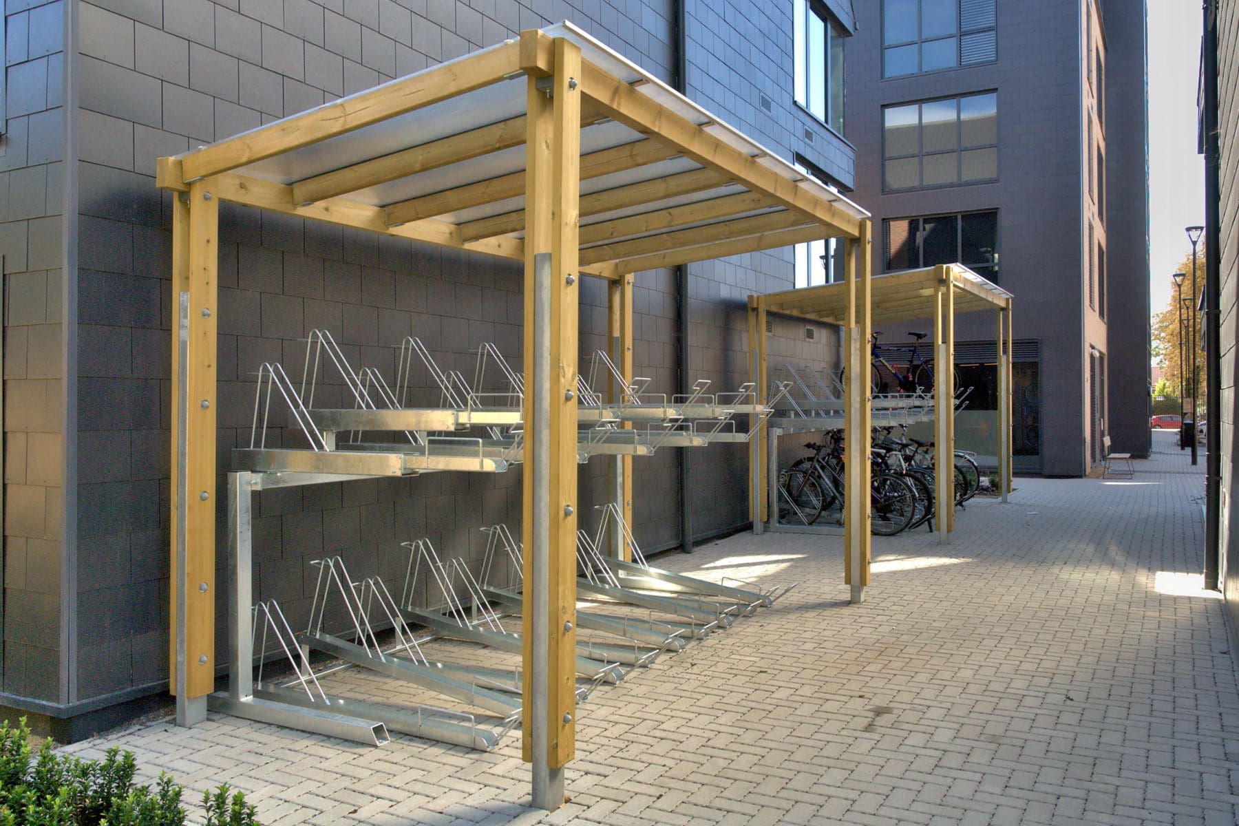 Outdoor canopies with wooden sides and see through plastic top covering metal two tiered bicycle stores