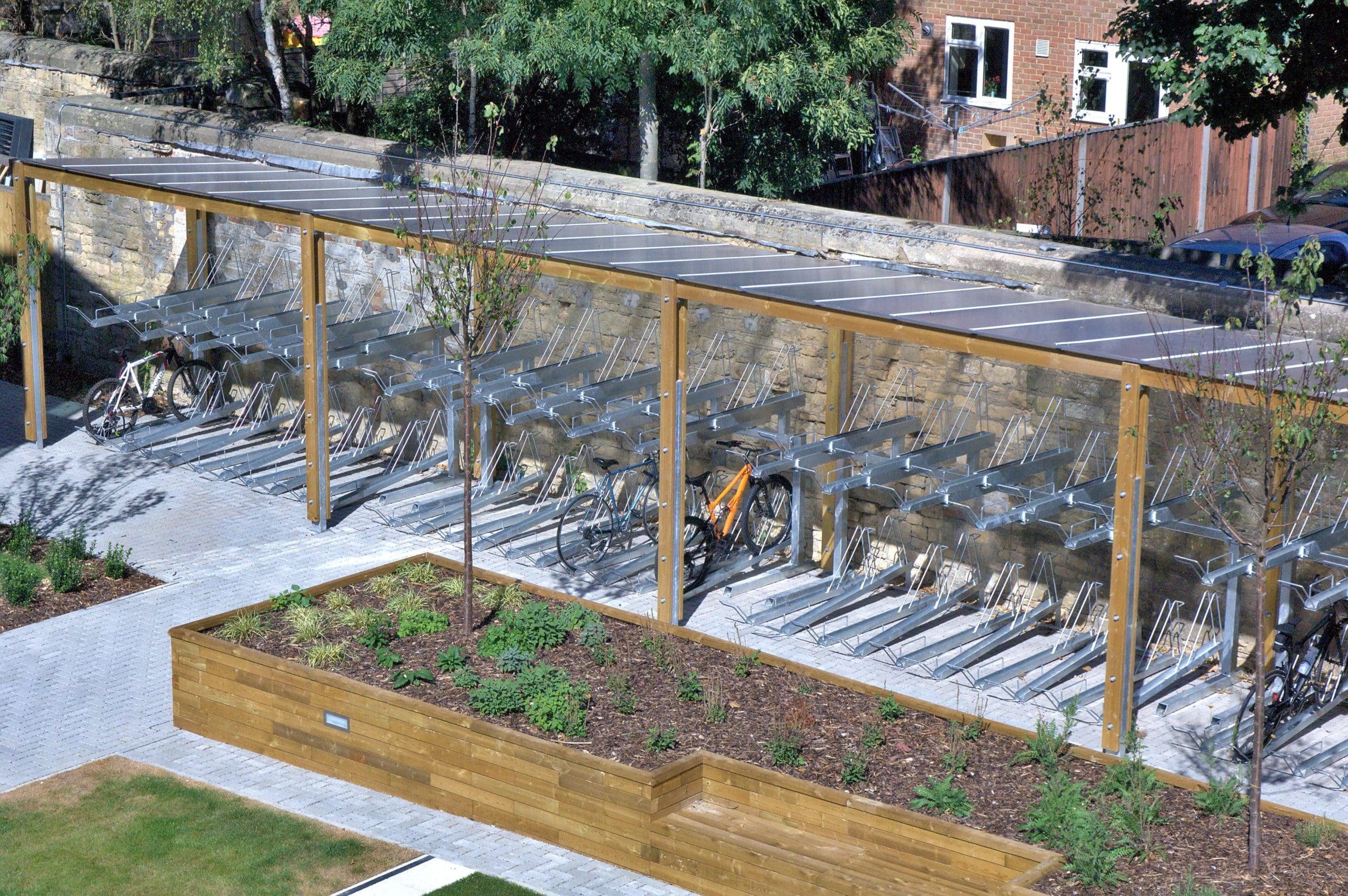 Long outdoor canopies with wooden sides and see through plastic top covering metal two tiered bicycle stores