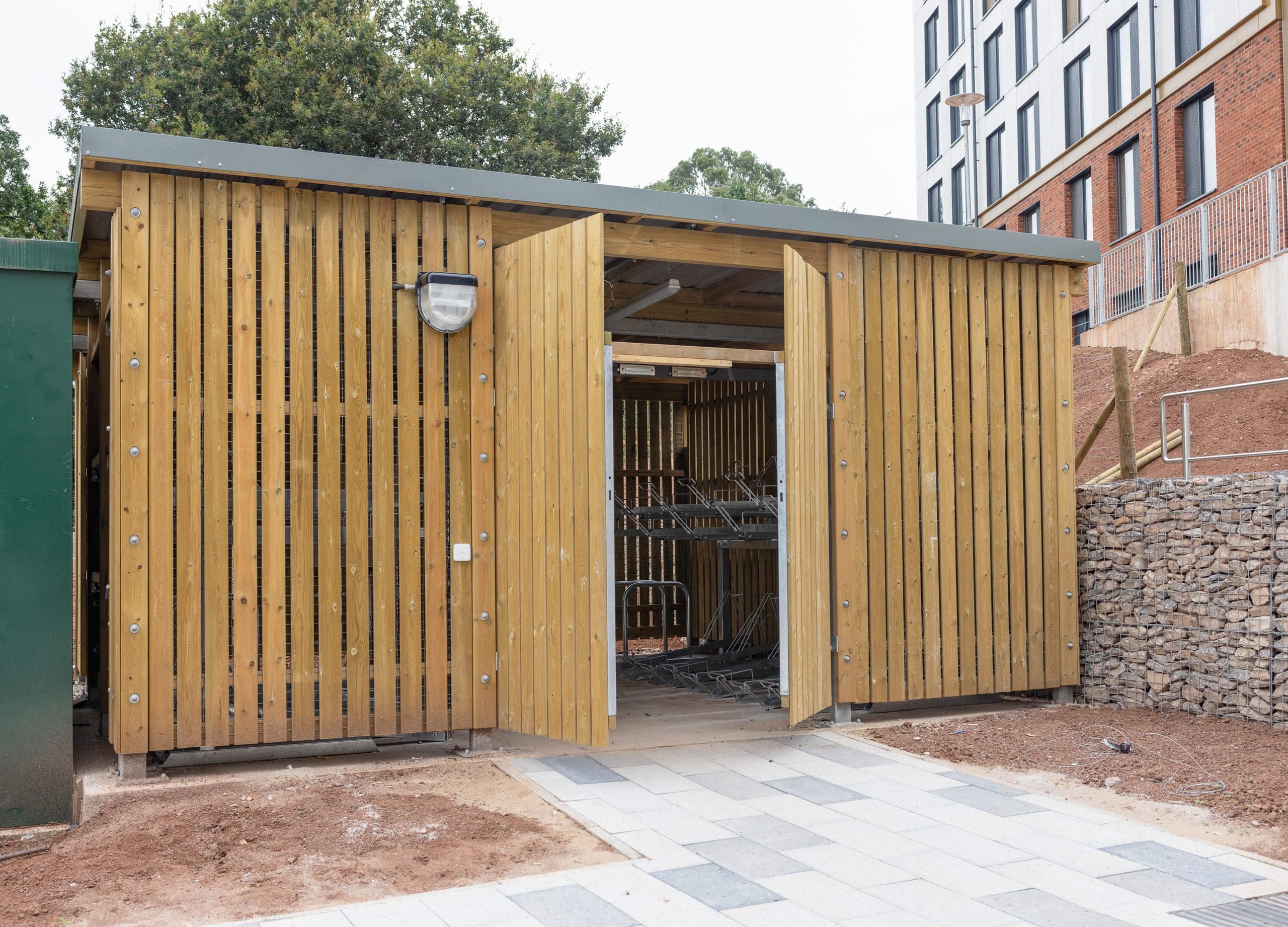 large wooden external cycle and bin storage unit with the door ajar to see bike racks