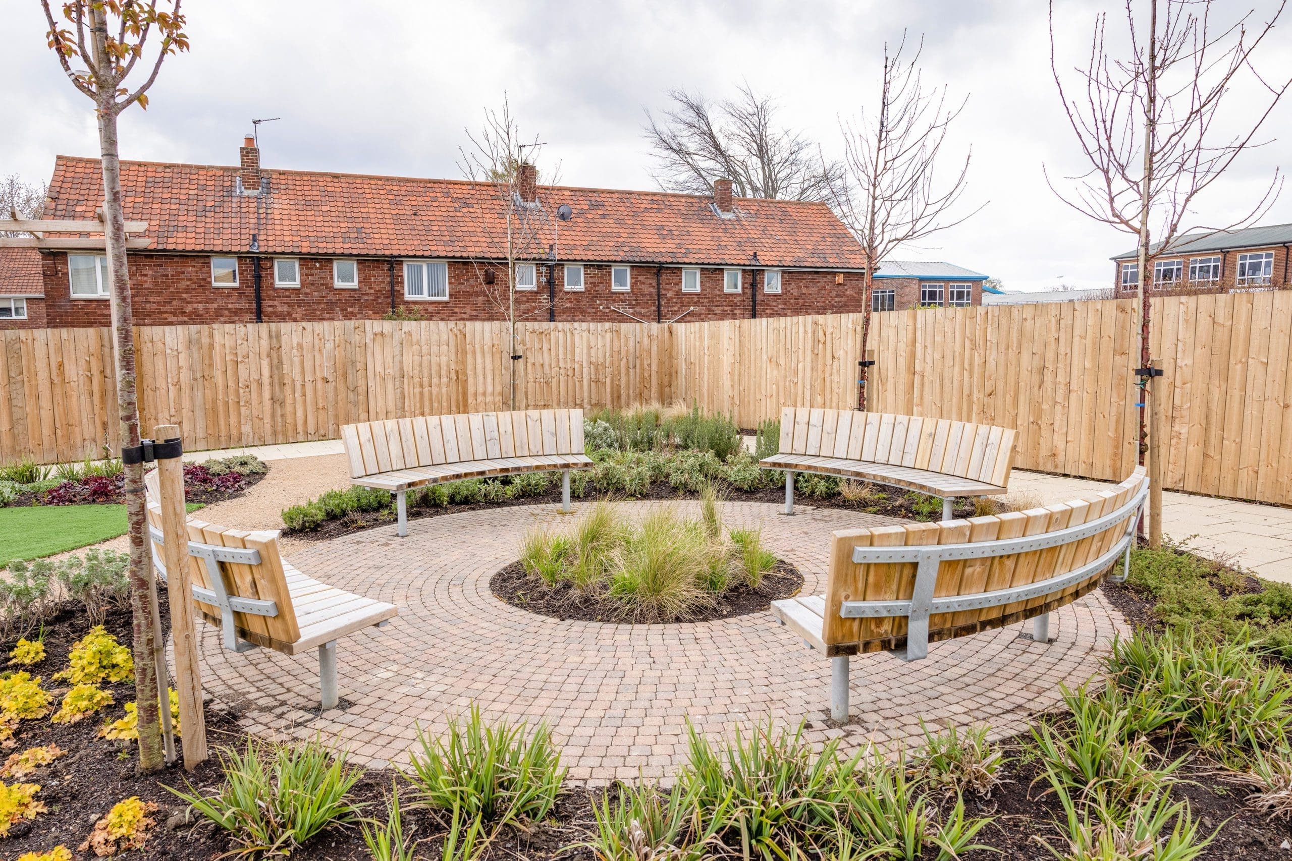 four-exterior-wooden-curved-benches-in-a-circle-around-surrounded-by-plants