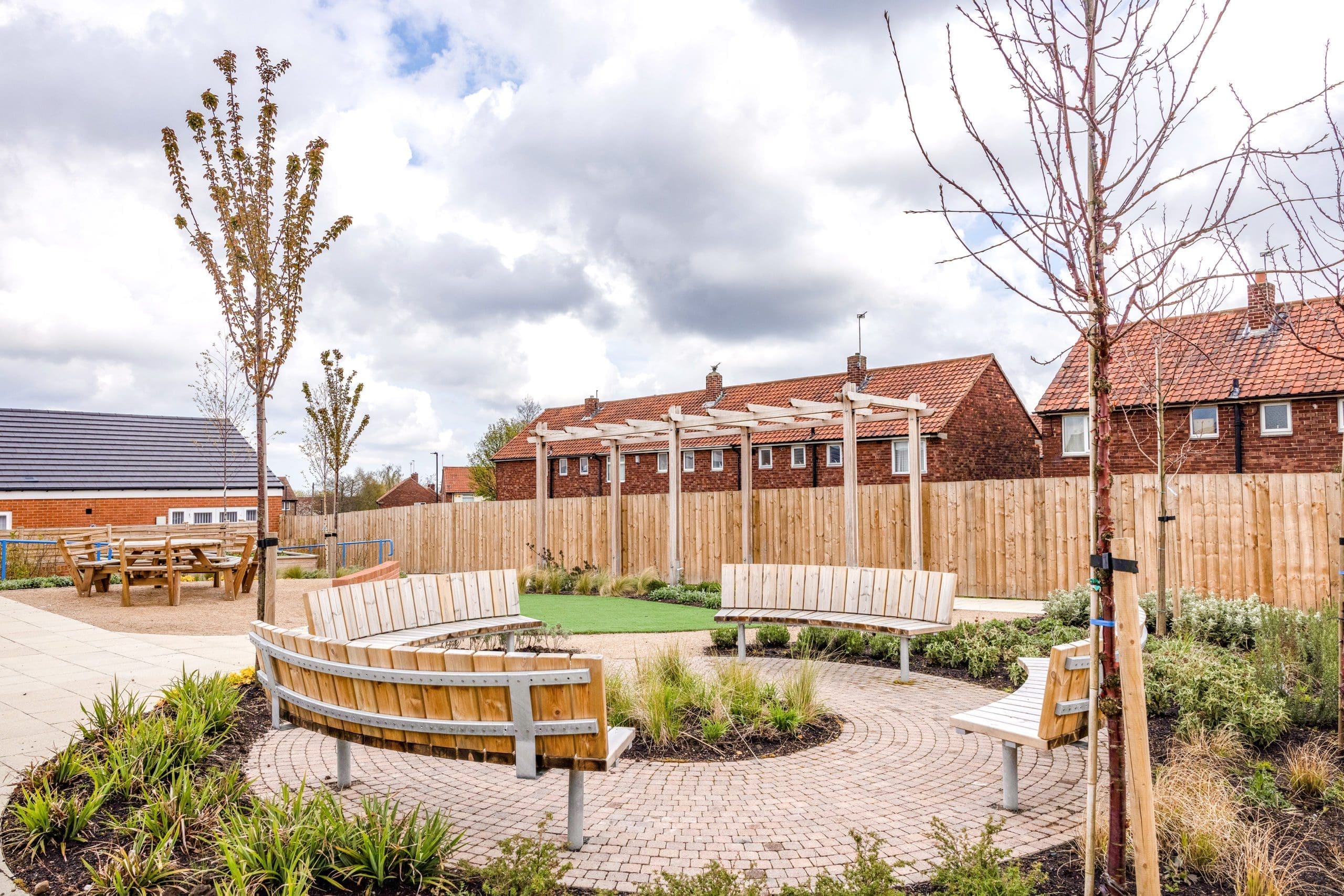 four-exterior-wooden-curved-benches-in-a-circle-around-surrounded-by-plants