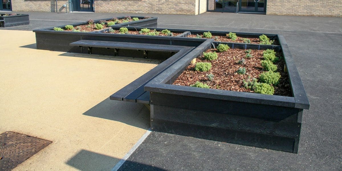 Outdoor black wooden L shaped raised planters with attached bench seating area