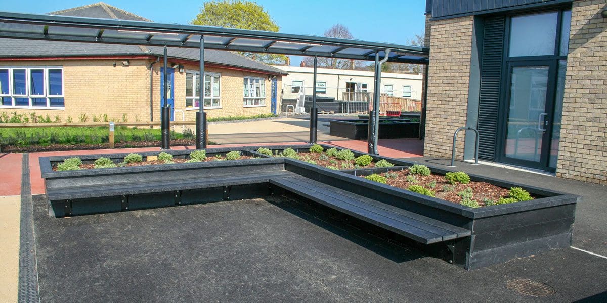 Outdoor black wooden L shaped raised planters with attached bench seating area