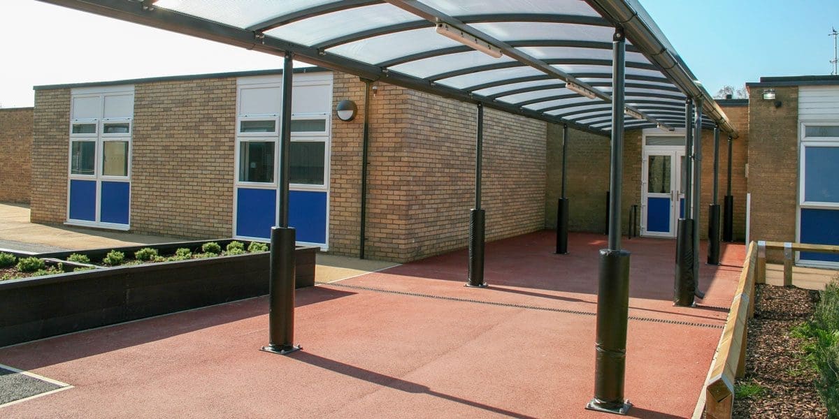 External black metal canopy with see through roof connecting two buildings