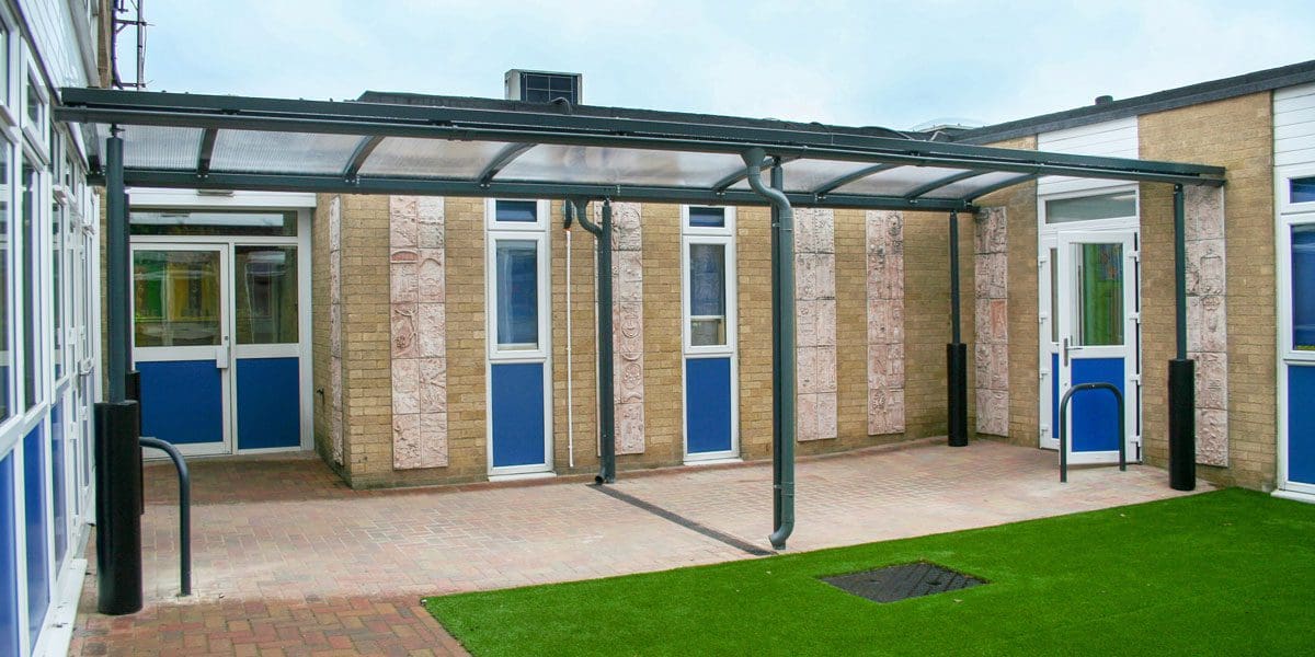 External black metal canopy with see through roof connecting two buildings