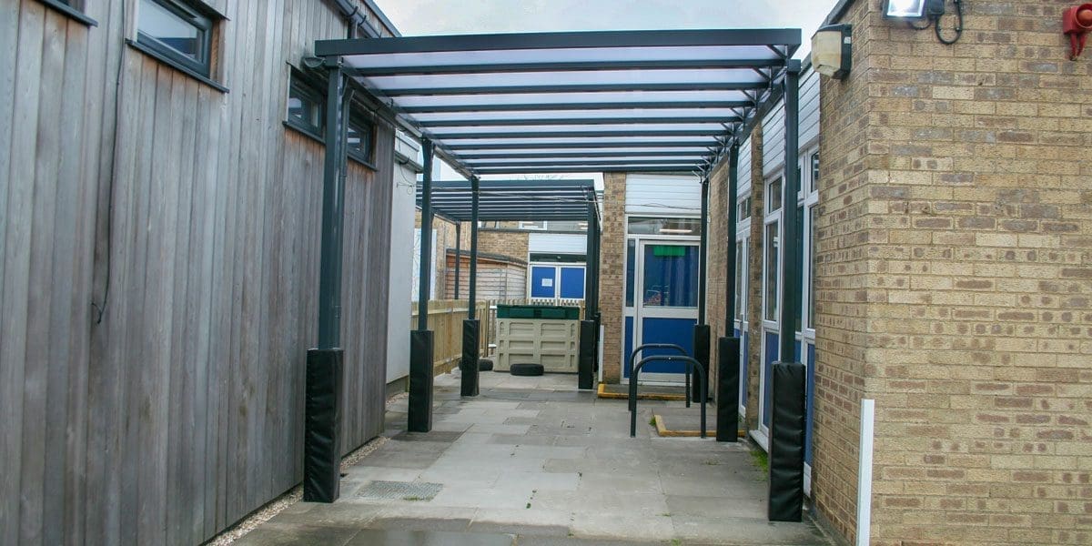 External black metal canopy with see through roof connecting two buildings