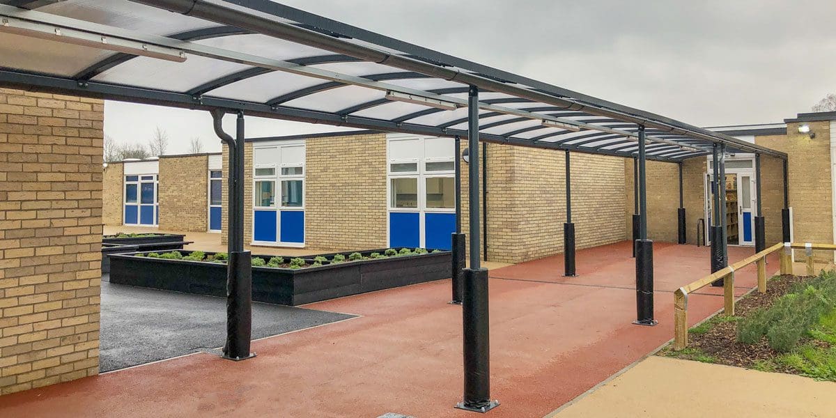 External black metal canopy with see through roof connecting two buildings