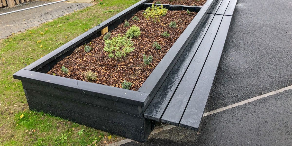 Outdoor black wooden L shaped raised planters with attached bench seating area