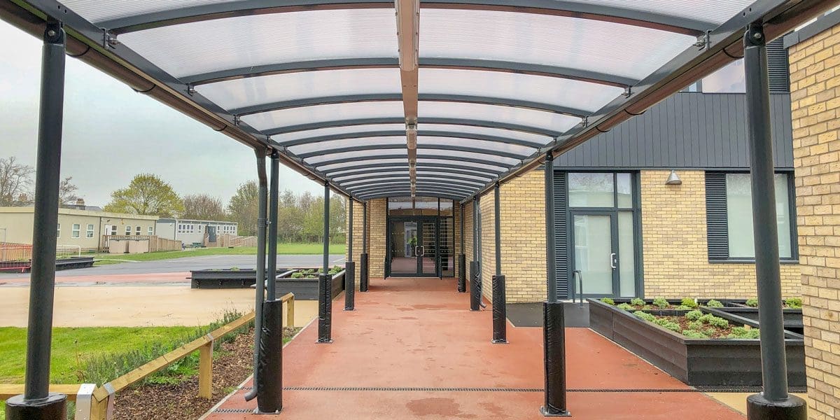 External black metal canopy with see through roof connecting two buildings