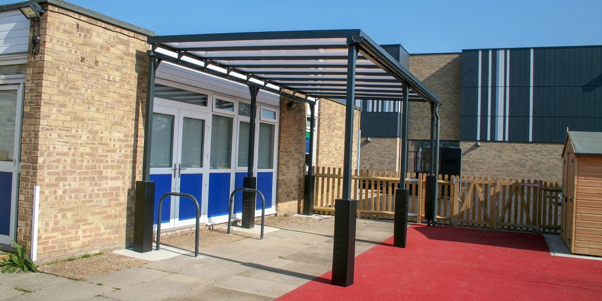 External black metal canopy with see through roof against side of building
