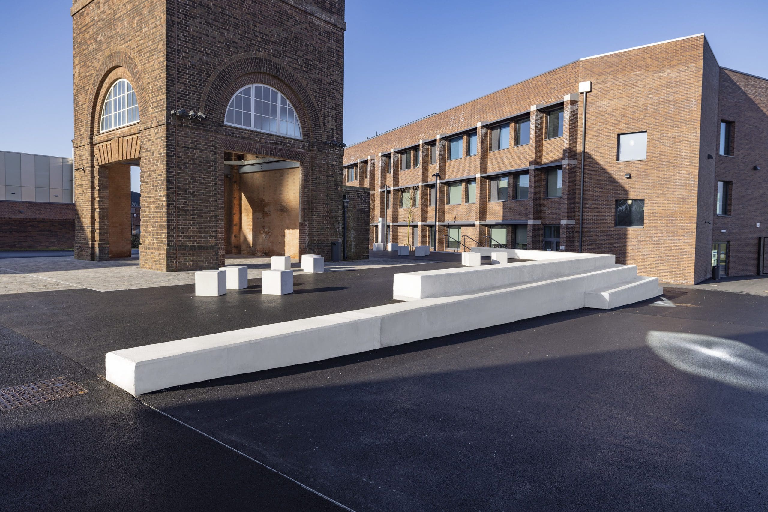 wide shot of exterior of the school showing concrete steps doubling as seating amongst square concrete seats