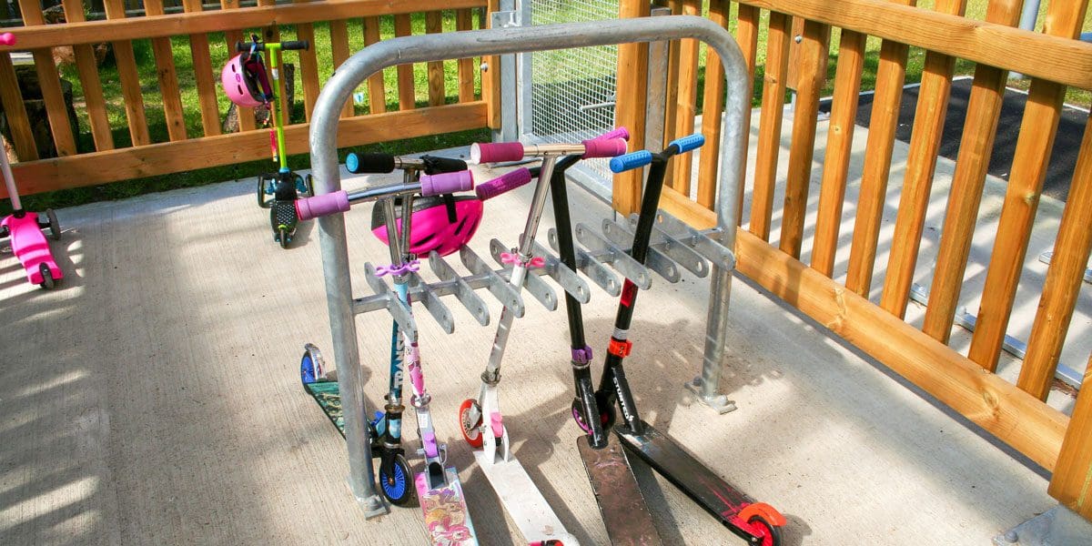 Close up of metal bike storage hoop in cycle shelter with childrens scooters parked