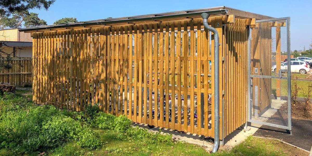 Exterior wooden bicycle shelter with inside storage and outside metal bike hoops