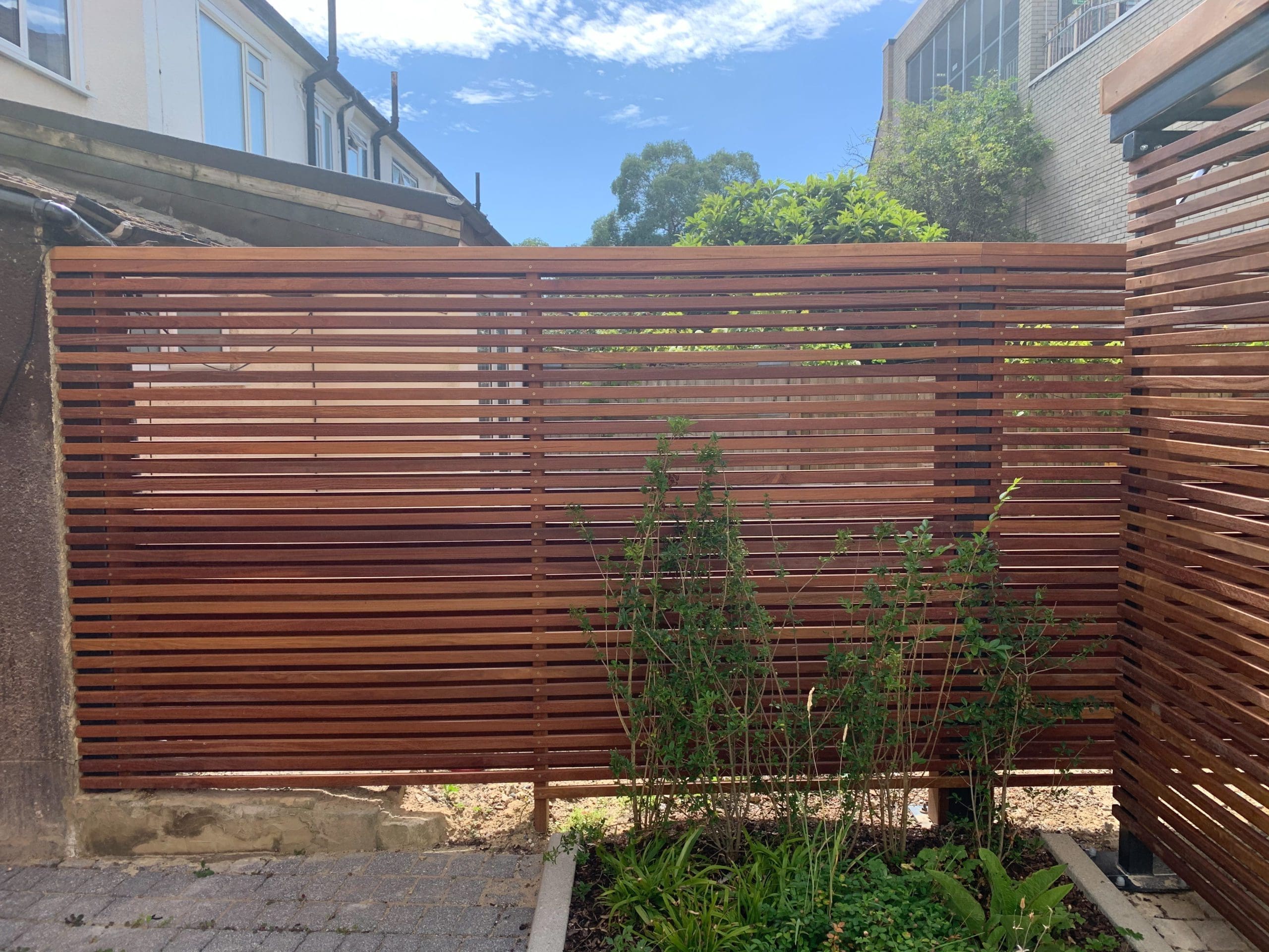 Edge of wooden bike storage canopy showing matching wooden fence