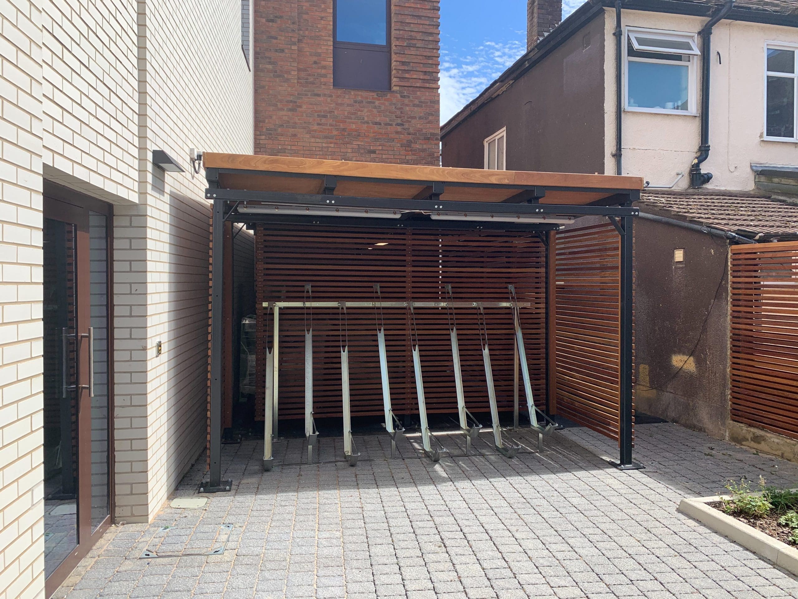 Metal bicycle storage rack for multiple bikes under wooden bike storage canopy