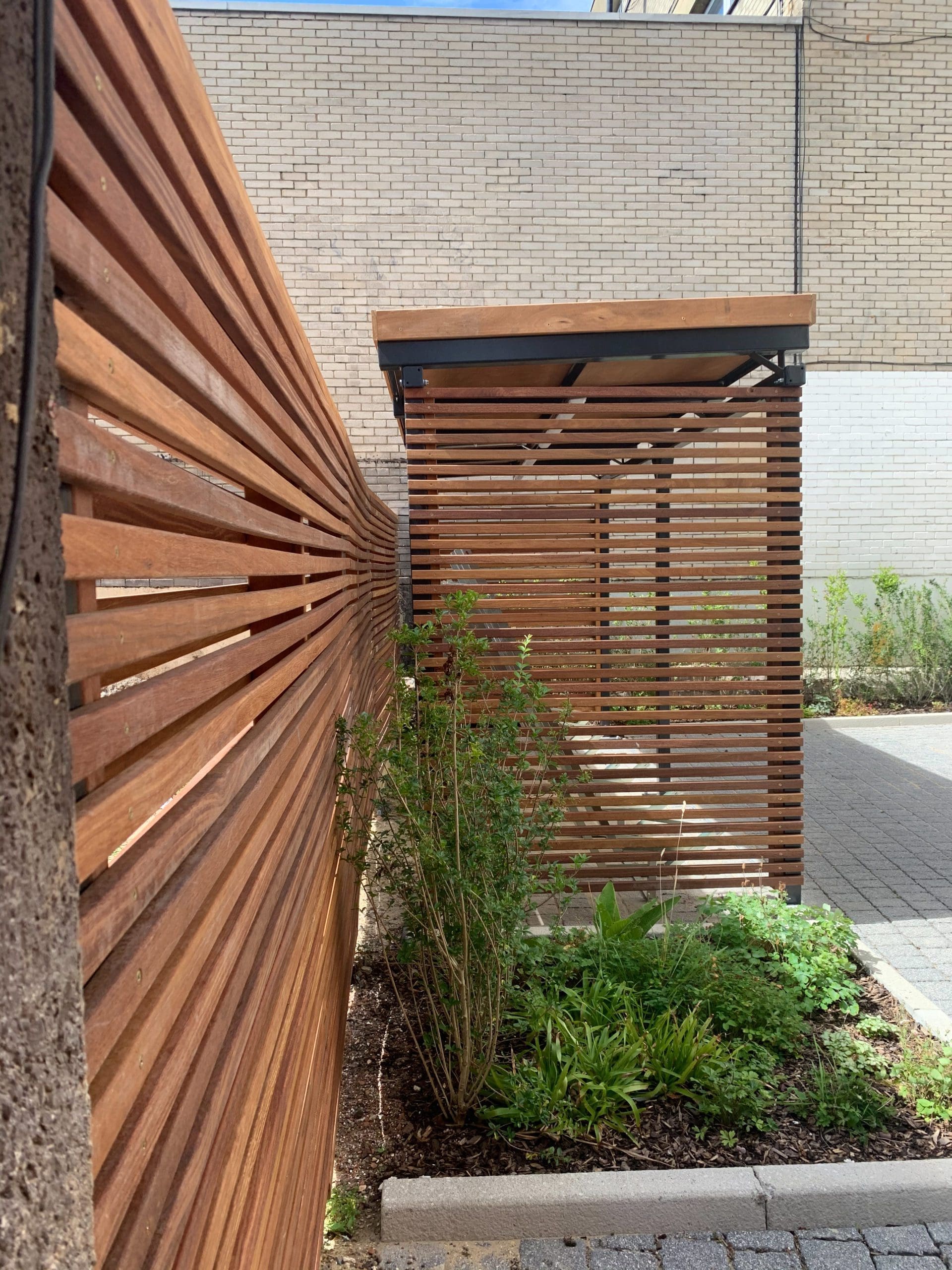 Side shot of wooden bike storage canopy and matching wooden fence