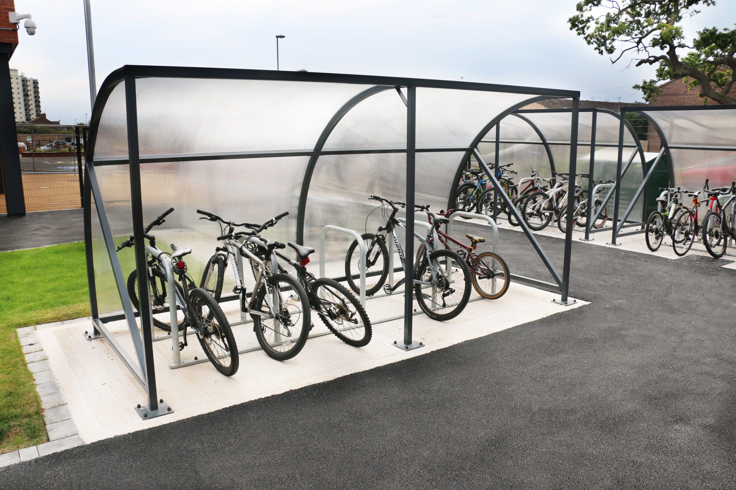 Exterior black metal curved bike shelter with frosted cover