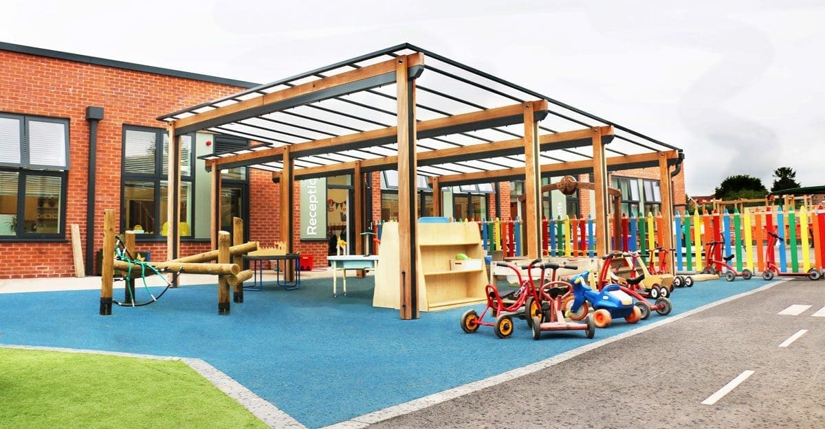 Wooden pergola canopy with black trim and seethrough rood covering colour childrens playground