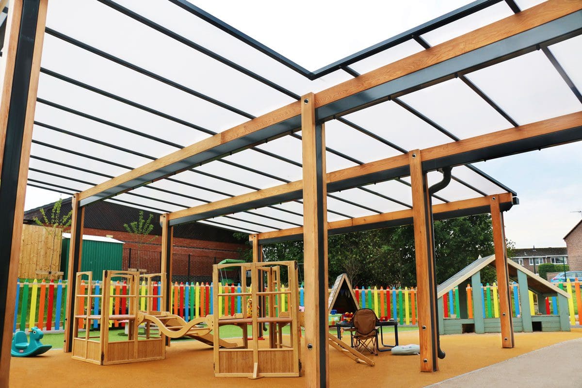 Wooden pergola canopy with black trim and seethrough rood covering colour childrens playground