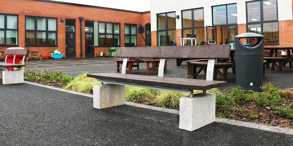 Outdoor wooden benches with concrete plinth legs infront of school